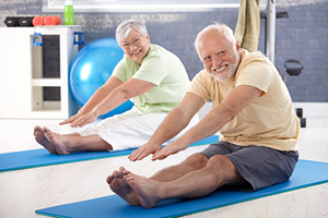 two seniors exercising on yoga mats